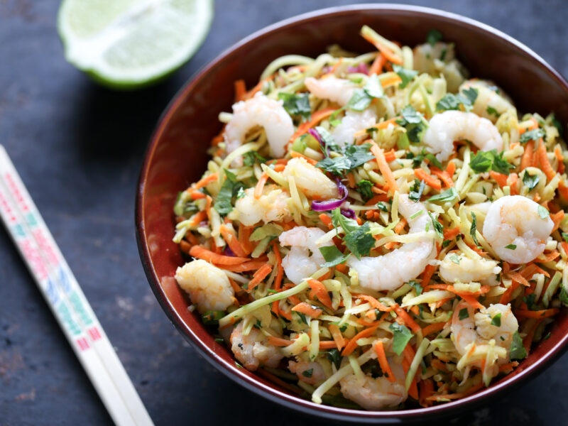 shrimp pad thai with chopsticks in red bowl on dark background