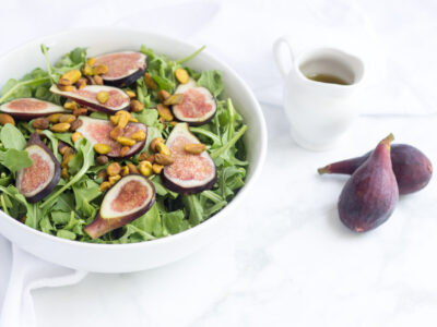 fig and pistachio salad in white bowl with figs