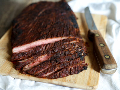 sliced coffee rubbed flank steak on cutting board with knife