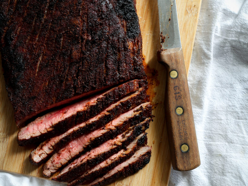 sliced coffee rubbed flank steak on cutting board with knife