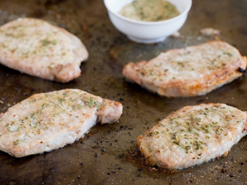 Four thin cut loin chops lightly browned and sprinkled with spices.