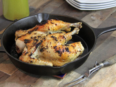 Roasted Spatchcocked Chicken in Cast Iron pan on wooden table.