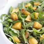Wide image of apricot and Arugula salad with balsamic vinaigrette in a white bowl