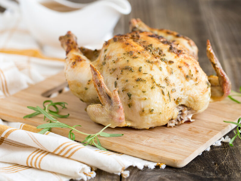 Wide image of Mustard and Rosemary Roasted Chicken on a light wood cutting board