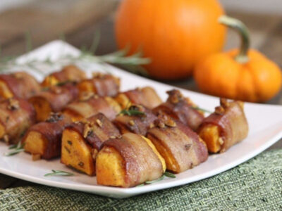 Bite-sized bacon-wrapped spiced pumpkin appetizers on white oblong plate