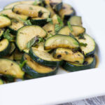 Minted Zucchini on a white plate (zucchini cut in half moons and garnished with chopped mint)