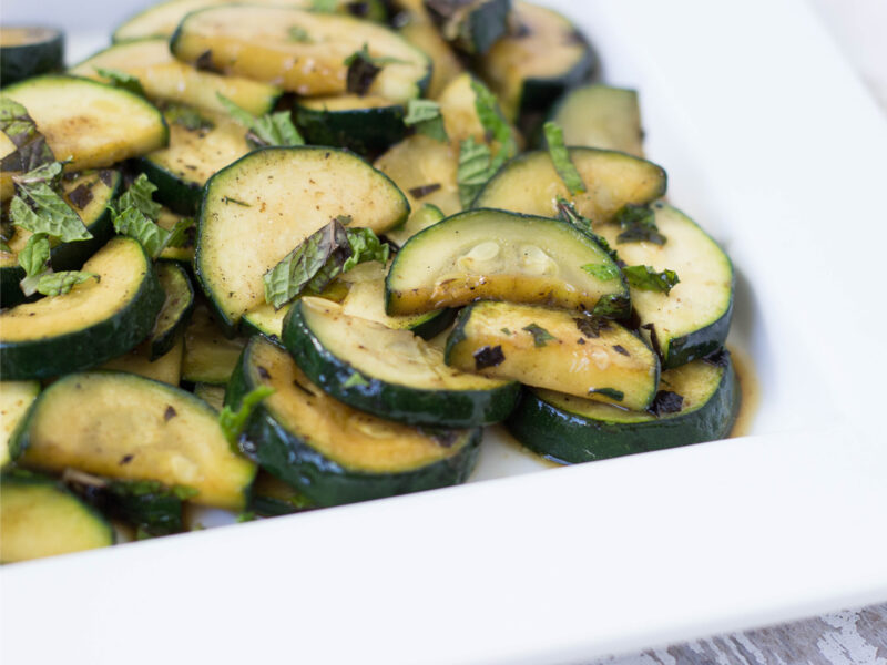 Minted Zucchini on a white plate (zucchini cut in half moons and garnished with chopped mint)