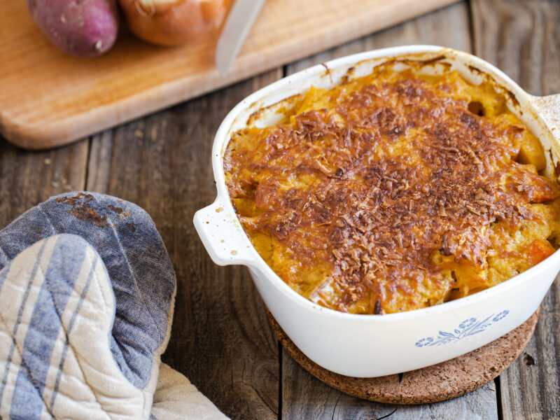 root vegetables in casserole dish with onions on cutting board