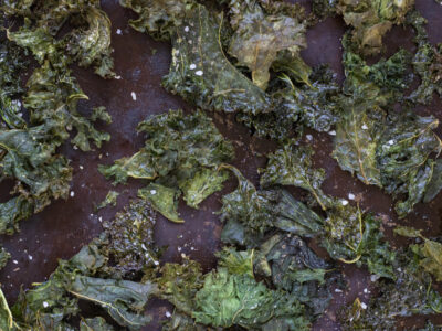 Close up of crispy baked Kale Chips on seasoned sheet tray.