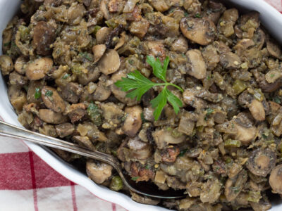 Image of eggplant and mushroom stuffing with bacon in an oval casserole dish with silver spoon.
