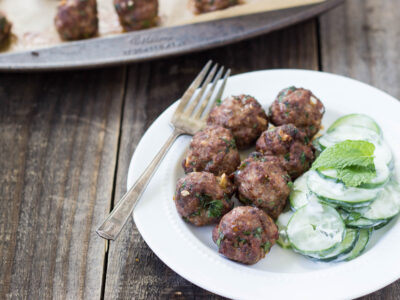 Several Hidden Liver Meatballs on a white plate with cucumber salad.