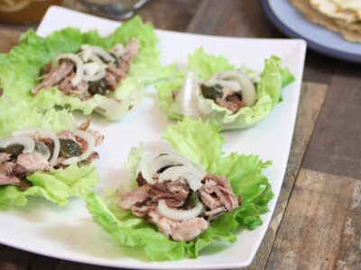 Close up of Pulled Pork Lettuce Wraps on a white plate on a wood table.