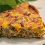 Pork and winter squash frittata on a white plate with salad greens.