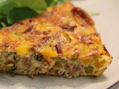 Pork and winter squash frittata on a white plate with salad greens.