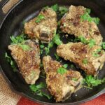 Dukka-crusted lamb garnished with parsley in cast iron pan.