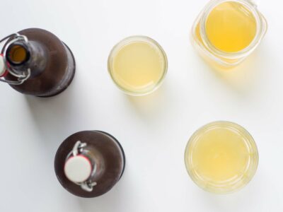 Overhead view of two brown bottles of kombucha along with a glass pitcher and two glasses full.