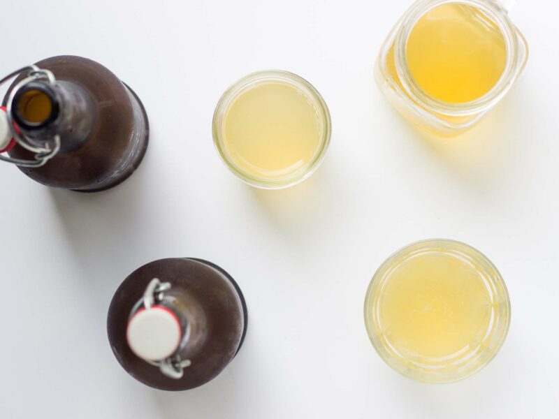 Overhead view of two brown bottles of kombucha along with a glass pitcher and two glasses full.