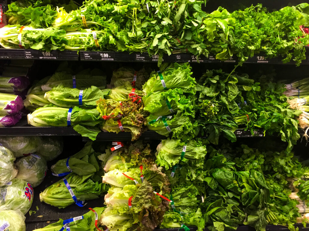 An image of various types of lettuce for sale in a produce department of a grocery store.