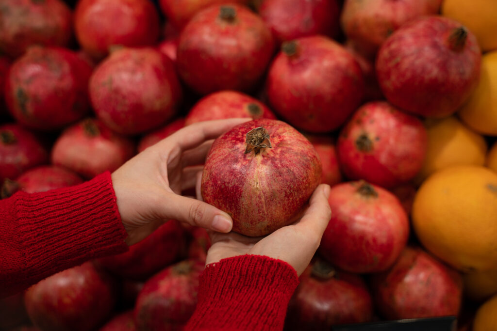 An image of a person selecting a pomegranate from the market.