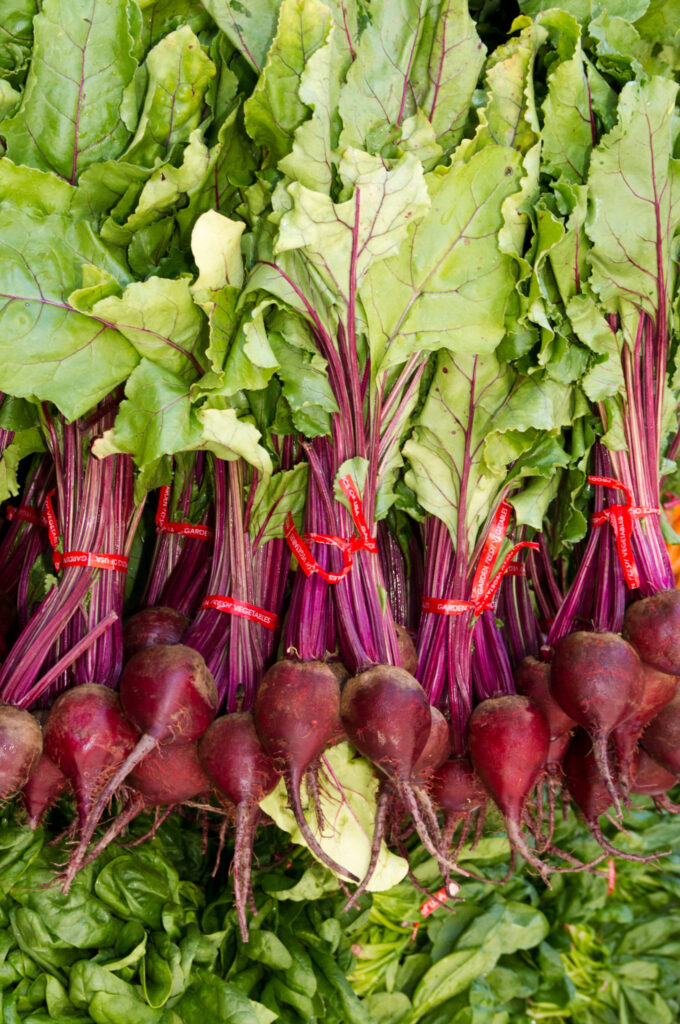 An image of beets and beet greens on display at the grocery store.