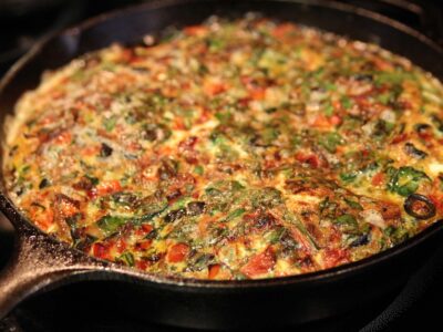 Close up of Bacon, Onion, and Olive Frittata in a cast iron pan.