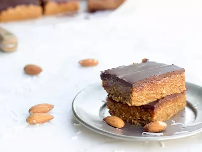almond coconut bars on silver plate with almonds and shredded coconut