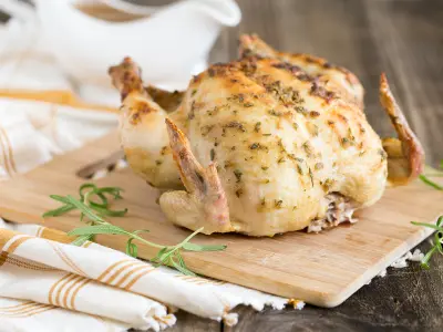 Wide image of Mustard and Rosemary Roasted Chicken on a light wood cutting board