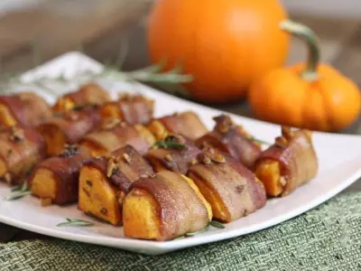 Bite-sized bacon-wrapped spiced pumpkin appetizers on white oblong plate