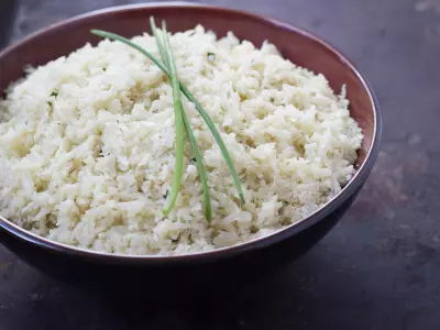 Wide shot of Ginger-Garlic Cauliflower Rice in a Bowl topped with a few sprigs of chives.
