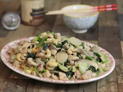 Cashew chicken stir-fry on oval plate on wood backdrop