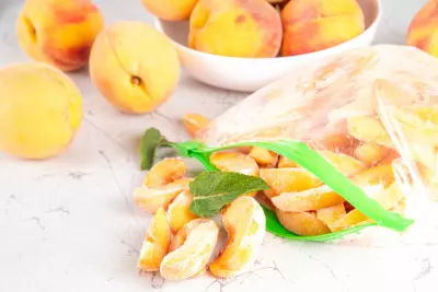 An image of frozen peach slices in a plastic bag, alongside fresh peaches.