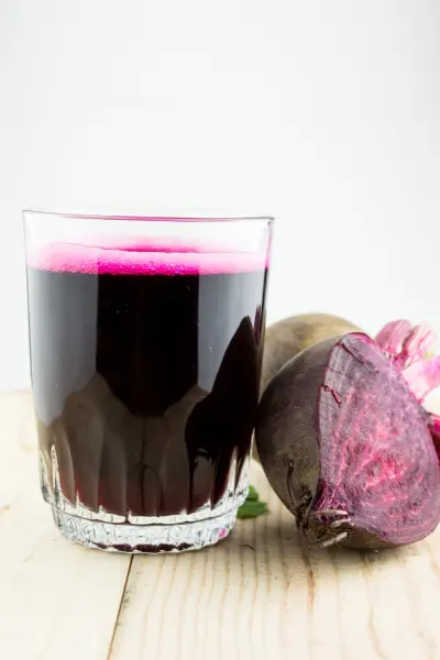 An image of a glass of beet juice with beet.